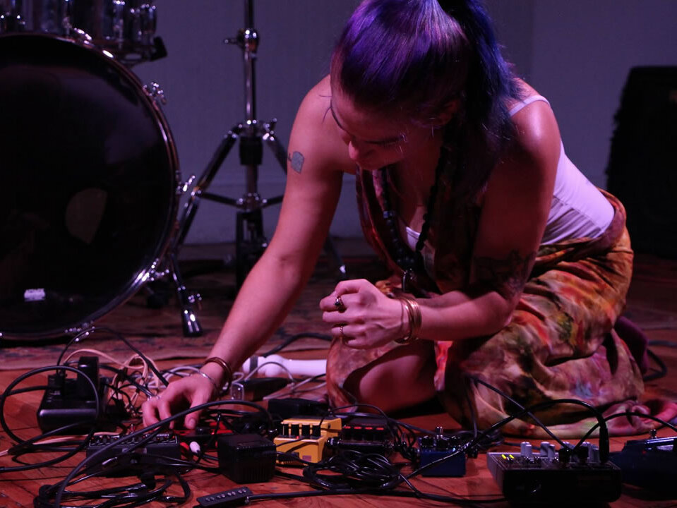 Umělkyně obklopená elektronikou a pedály během noise setu